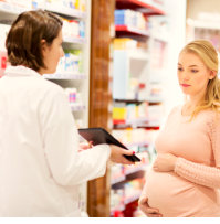 a pharmacist showing a note to a pregnant woman